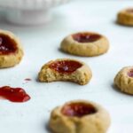 Scattered Almond Thumbprint Cookies with bite missing