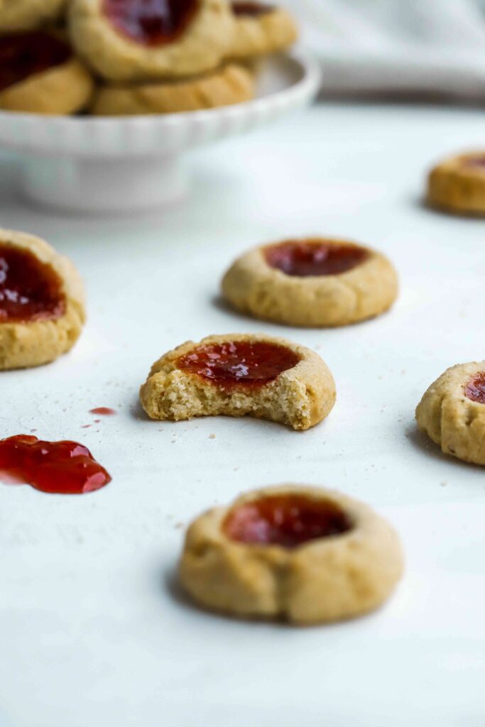 Scattered Almond Thumbprint Cookies with bite missing