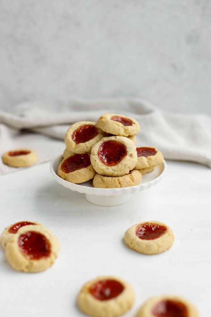 Almond Thumbprint Cookies on a small cake stand and scattered