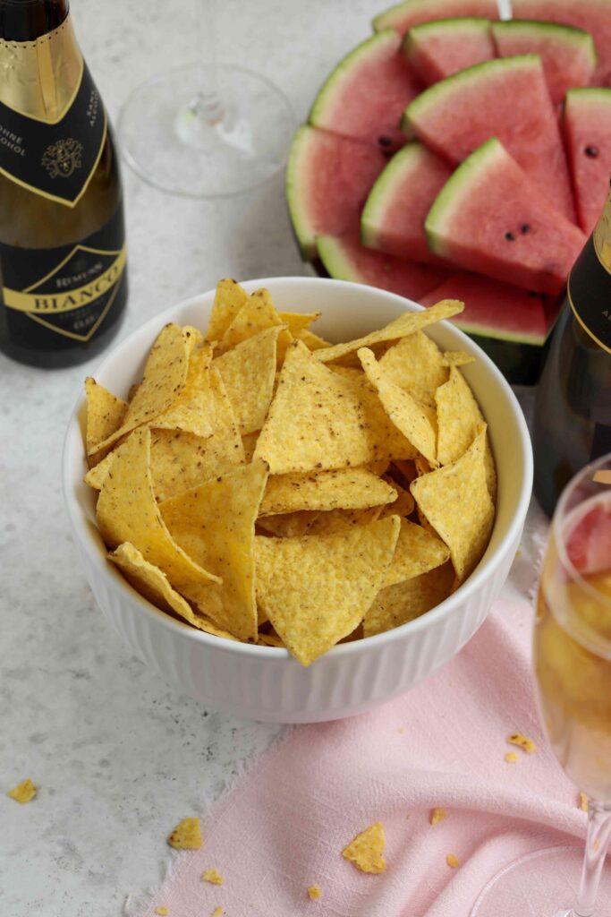 Eine Schüssel mit Tortilla Chips, Wassermelone im Hintergrund